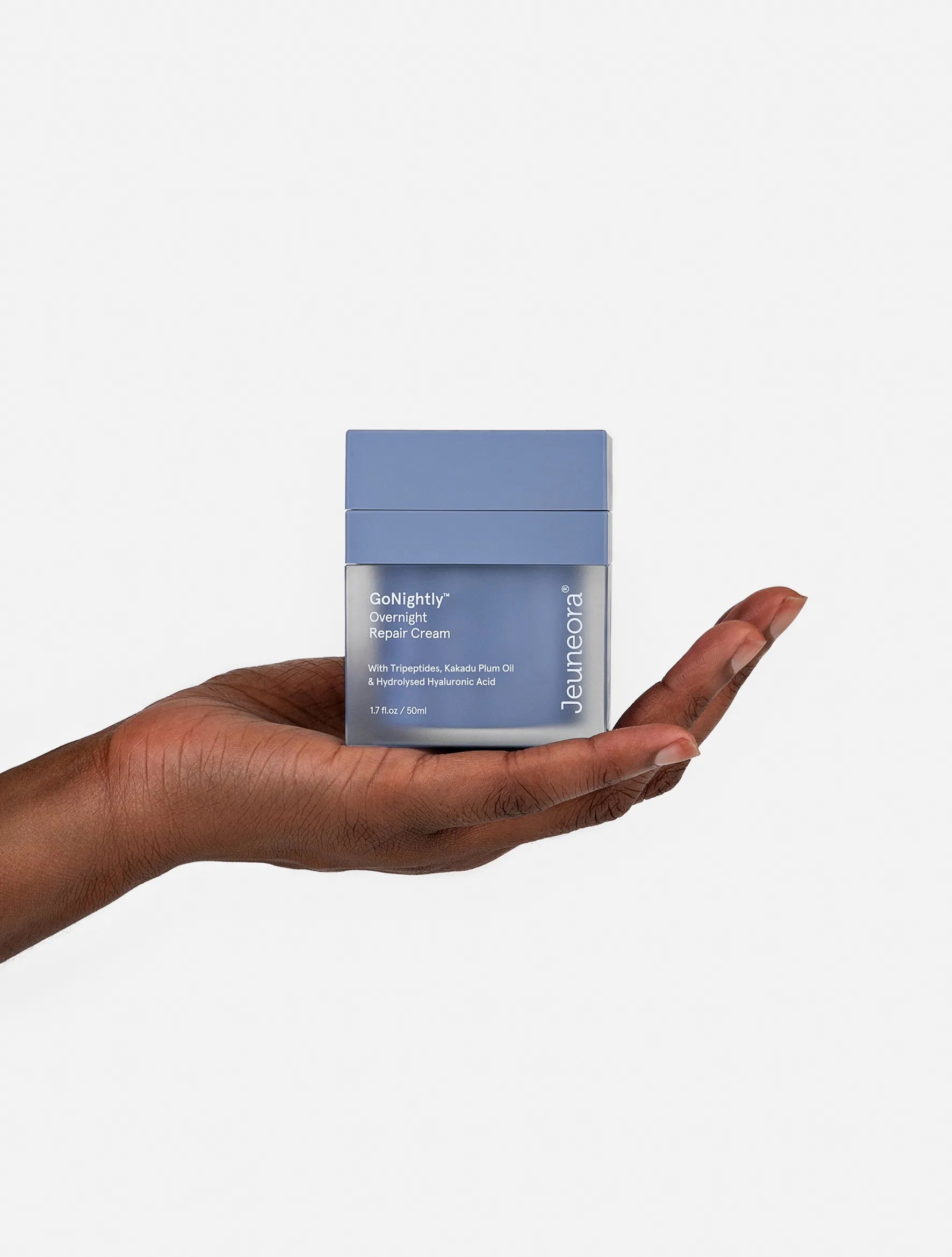 Hand holding Jeuneora GoNightly Overnight Repair Cream 50ml jar against a white background