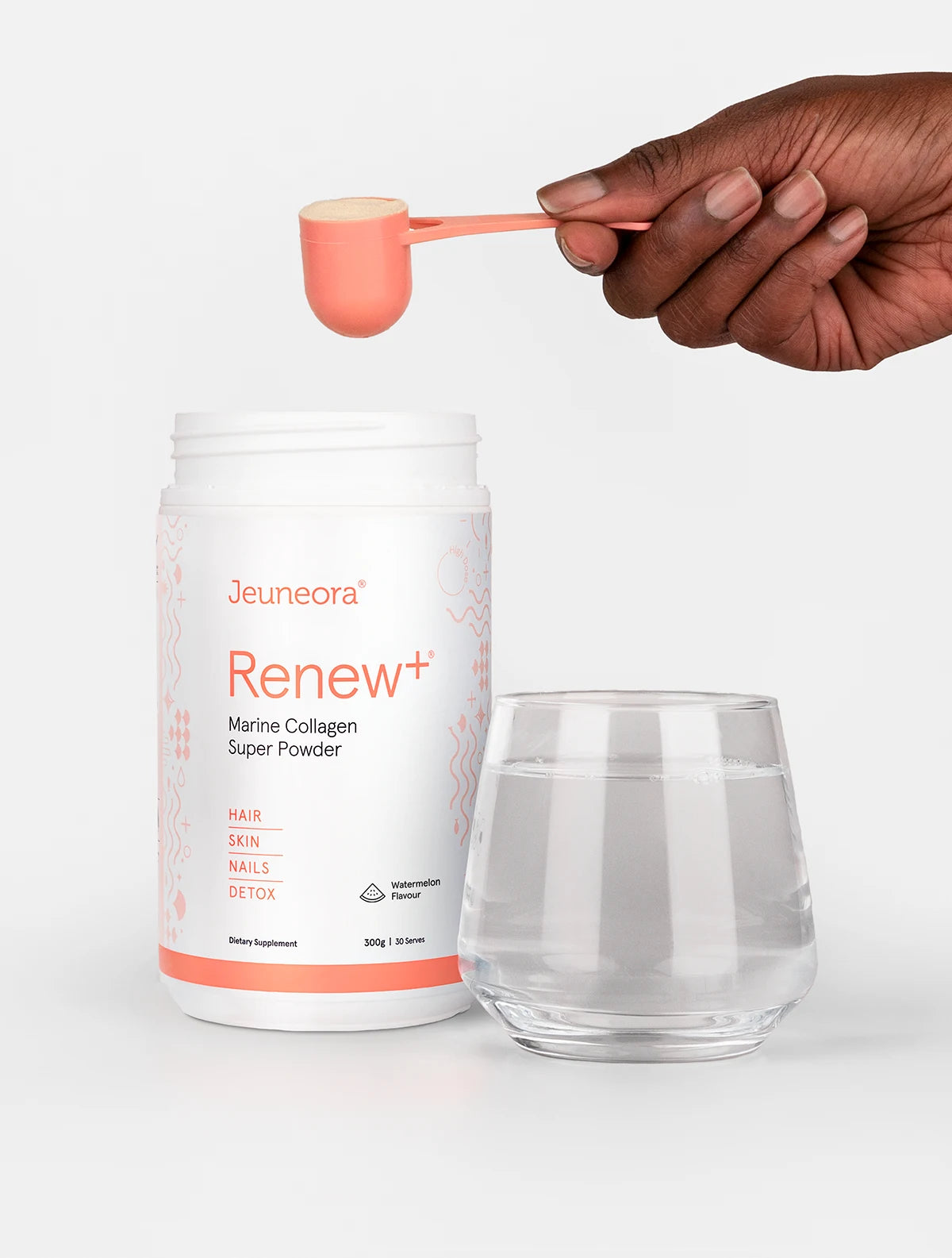 A person holding a scoop of Jeuneora Renew+ Watermelon flavour - a glass of water sits in the foreground