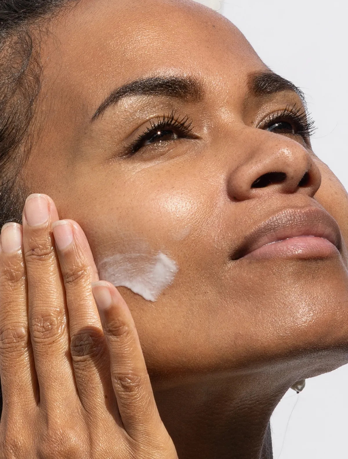 woman applying serum to her glowing face