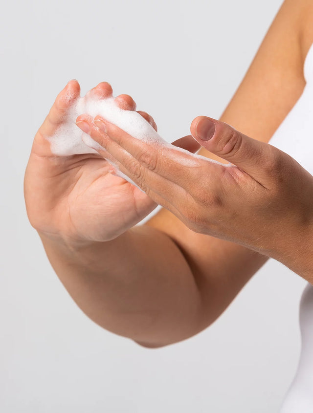 Woman rubbing foaming face cleanser in hands